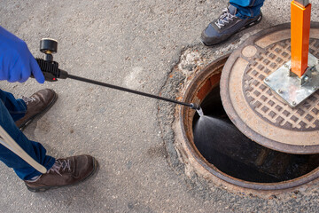 Person lifting sewer with magnet and disinfecting sewer