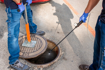 Person lifting sewer with magnet and disinfecting sewer