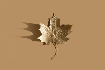 Shiny Golden leaf on nude color background. Flat lay, top view. Minimal autumn composition concept.