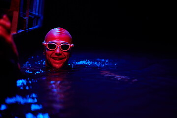 authentic triathlete swimmer having a break during hard training on night neon gel light