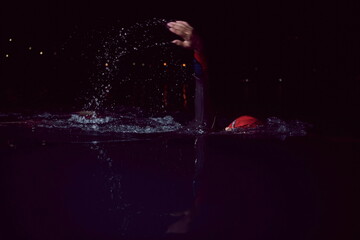 triathlon athlete swimming in dark night wearing wetsuit