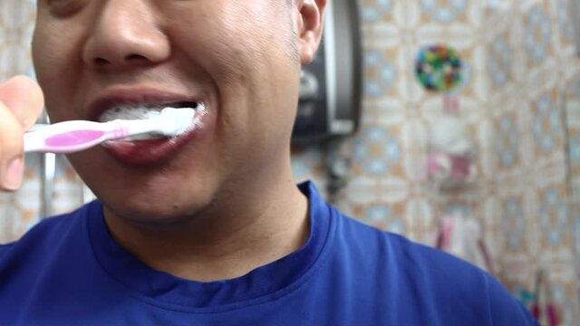 Local lifestyle Chinese man brushing teeth at home. Close up. Front view.