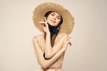 Romantic woman in a hat and dress on a light background gestures with her hands portrait fun emotions cropped view