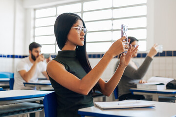 College students recording the lecture in classroom with their cell phones.