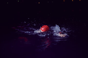 triathlon athlete swimming in dark night wearing wetsuit