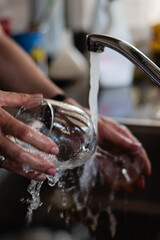 primer plano de manos lavando vajilla platos cubiertos copas de cristal esponja y jabon 