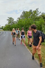 Young people walking by the roadside going on a summer vacation trip