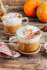 Pumpkin spiced latte or coffee in a glass on a vintage table. Autumn or winter hot drink.