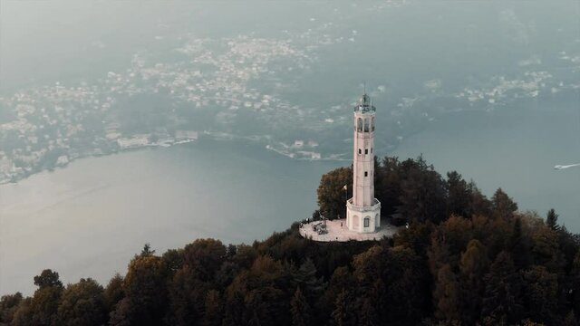Volta Lighthouse (Faro Voltiano) On The Hilltop Overlooking The Como Lake And City On A Misty Morning In Brunate, Italy, Europe. - aerial drone shot