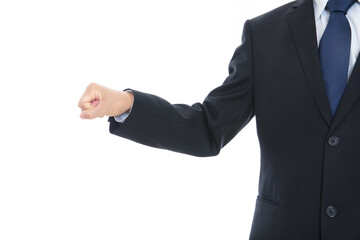 Male in black suit in front of white background makes fist and stretches out hand