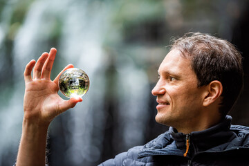 Blackwater Falls famous Elakala waterfall closeup of man holding crystal ball reflection in State Park in West Virginia during autumn fall season