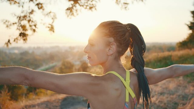 Determined slim sportswoman with beautiful braids doing strength yoga poses stretching body in the morning sunrise. Stunning natural landscape. Summer. Inspiration.