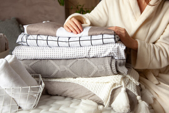 Beautiful Woman In Winter Thick Warm Robe Is Sitting And Neatly Folding Bed Linens And Bath Towels