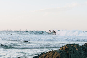 Surfers dropping in on each other or sharing wave at snapper rocks, Queensland