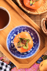 Delicious ripe persimmon fruit on wooden tray.  