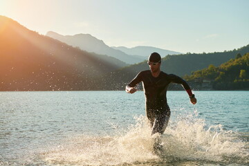 triathlon athlete starting swimming training on lake