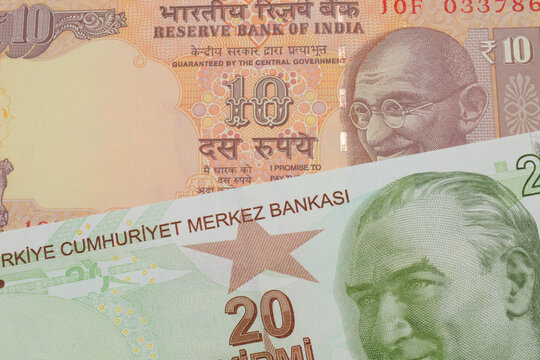A macro image of a orange ten rupee bill from India paired up with a green, twenty Turkish lira bank note.  Shot close up in macro.