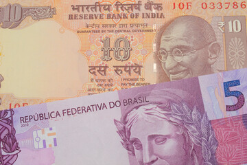 A macro image of a orange ten rupee bill from India paired up with a pink and purple five real bank note from Brazil.  Shot close up in macro.