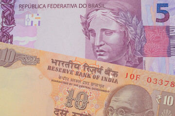 A macro image of a orange ten rupee bill from India paired up with a pink and purple five real bank note from Brazil.  Shot close up in macro.