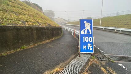 霧の濃い朝の田舎の道路と工事の看板