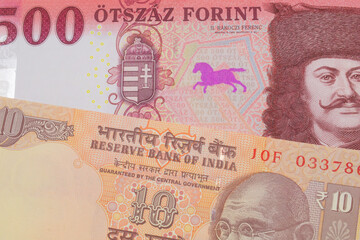 A macro image of a orange ten rupee bill from India paired up with a red and white five hundred forint note from Hungary.  Shot close up in macro.