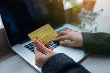 Close up Woman Hands holding plastic credit card and using laptop. Toned picture,Online shopping, e-commerce, internet banking, spending money, working from home concept