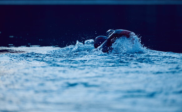 triathlon athlete swimming on lake in sunrise wearing wetsuit