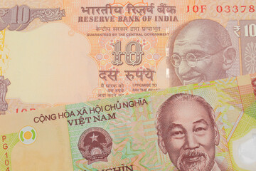 A macro image of a orange ten rupee bill from India paired up with a colorful, plastic ten thousand dong note from Vietnam.  Shot close up in macro.