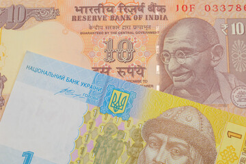 A macro image of a orange ten rupee bill from India paired up with a blue, white and yellow one hyrvnia bank note from Ukraine.  Shot close up in macro.