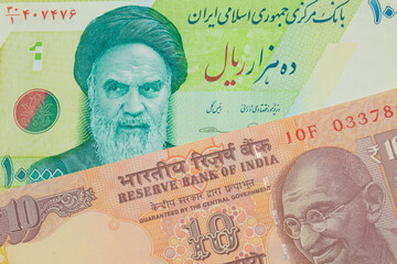 A macro image of a orange ten rupee bill from India paired up with a blue and green ten thousand rial bank note from Iran.  Shot close up in macro.