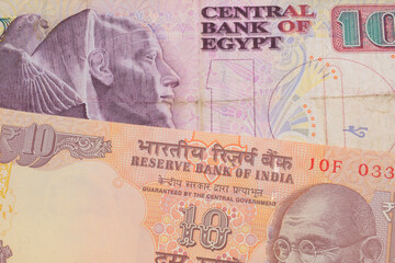 A macro image of a orange ten rupee bill from India paired up with a pink and purple ten pound bank note from Egypt.  Shot close up in macro.