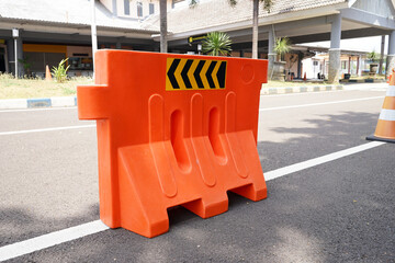 Orange water barrier on road, water-filled plastic barriers.