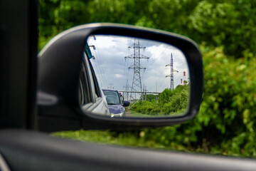 a lot of power transmission towers in the rear-view mirror of a car
