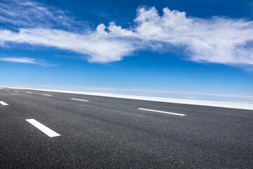 Naklejka premium Empty asphalt road and blue sky with white clouds scenery.