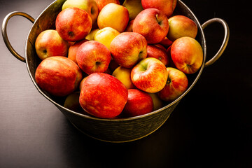 Ripe red apples in washtub on dark background top view