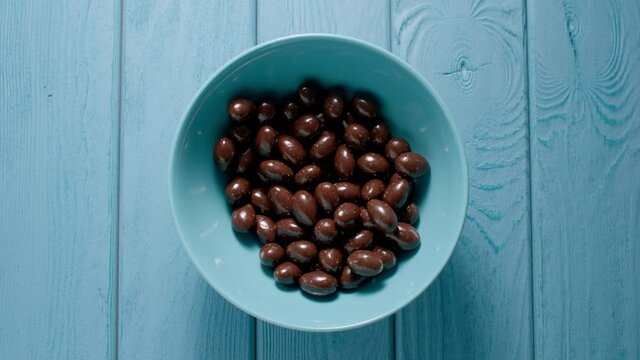 Male hand taking a handfull of chocolate candy from a bowl. Top view.
