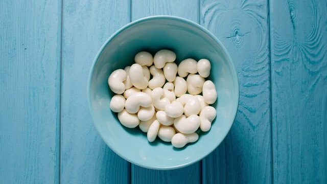 TOP VIEW: Male hand taking a lot of white chocolate candy from a bowl.