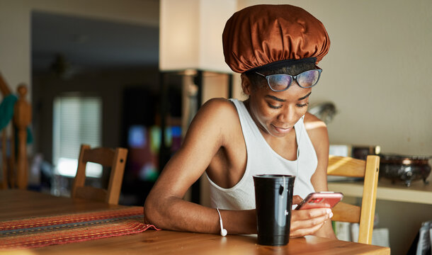 african american woman wearing showercap looking at smartphone during morning routine