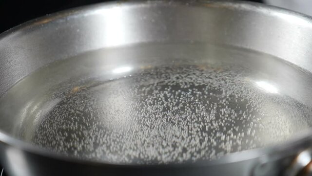 Water boiling in saucepan, Bubbles from boiling water. macro shot of small and big air bubbles in water rising in slow motion. Hot water for cooking Italian pasta in luxury restaurant. Full hd