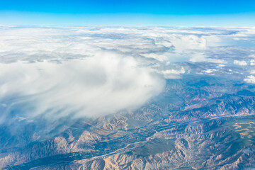 Fototapeta premium Aerial view above the clouds and mountain peaks on a sunny day.mountain view from airplane.