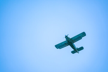 Retro green biplane plane in the blue sky