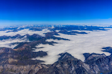 Aerial view above the clouds and mountain peaks on a sunny day.mountain view from airplane.