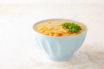 Pea soup with pieces of bacon and parsley in blue bowl on a white background.