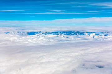 Naklejka na ściany i meble Aerial view above the clouds and misty mountain peaks covered with snow on a sunny day.China Tibet.