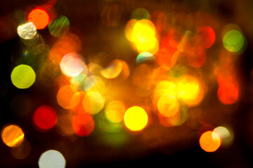 Multi-colored large bokeh glows on a dark background. Christmas lights garlands with blurred focus. Abstract background