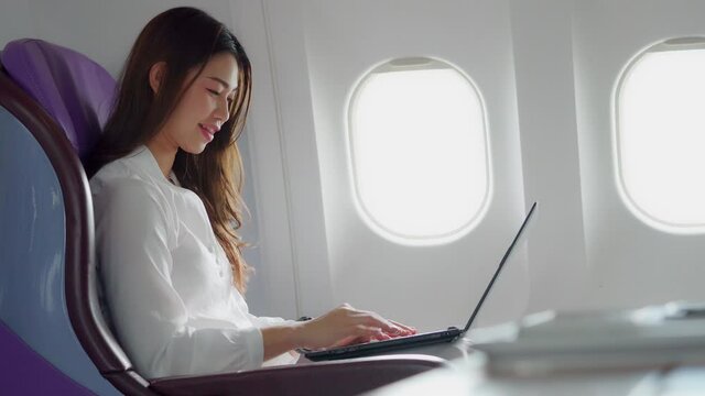 Asian young woman using laptop sitting near windows at first class on airplane during flight,Traveling and Business concept