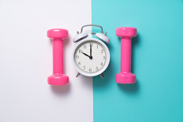 Time for exercising alarm clock and dumbbell with colorful background