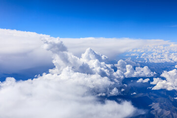 Naklejka premium Aerial view above the clouds and mountain peaks on a sunny day.mountain view from airplane.