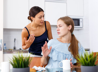 Emotional quarrel between two young women friends in kitchen interior