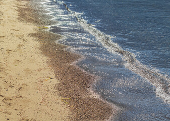 Small waves coming from the lake into the sandy beach. Travel photo, selective focus, copy space for text, nobody.